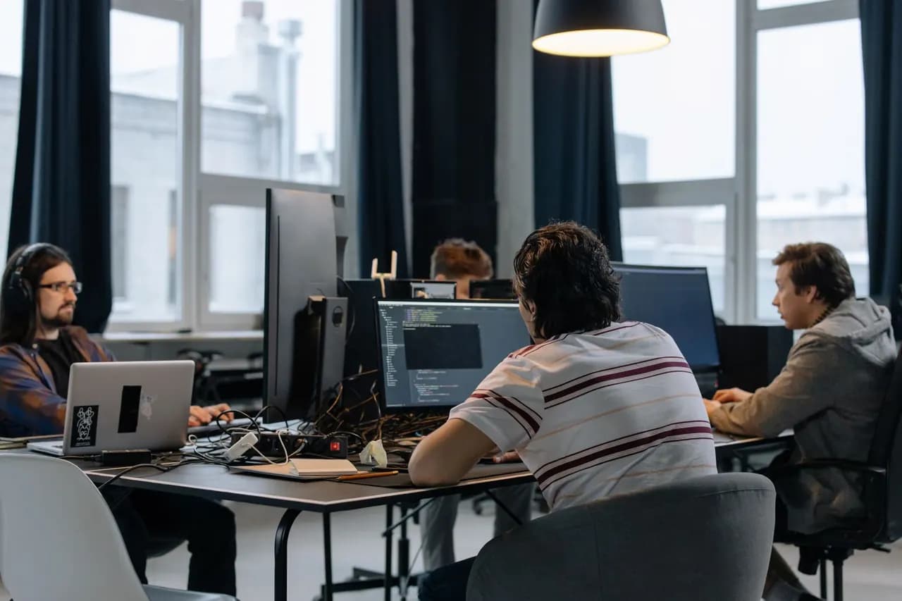 Development team collaborating at workstations in a software company office