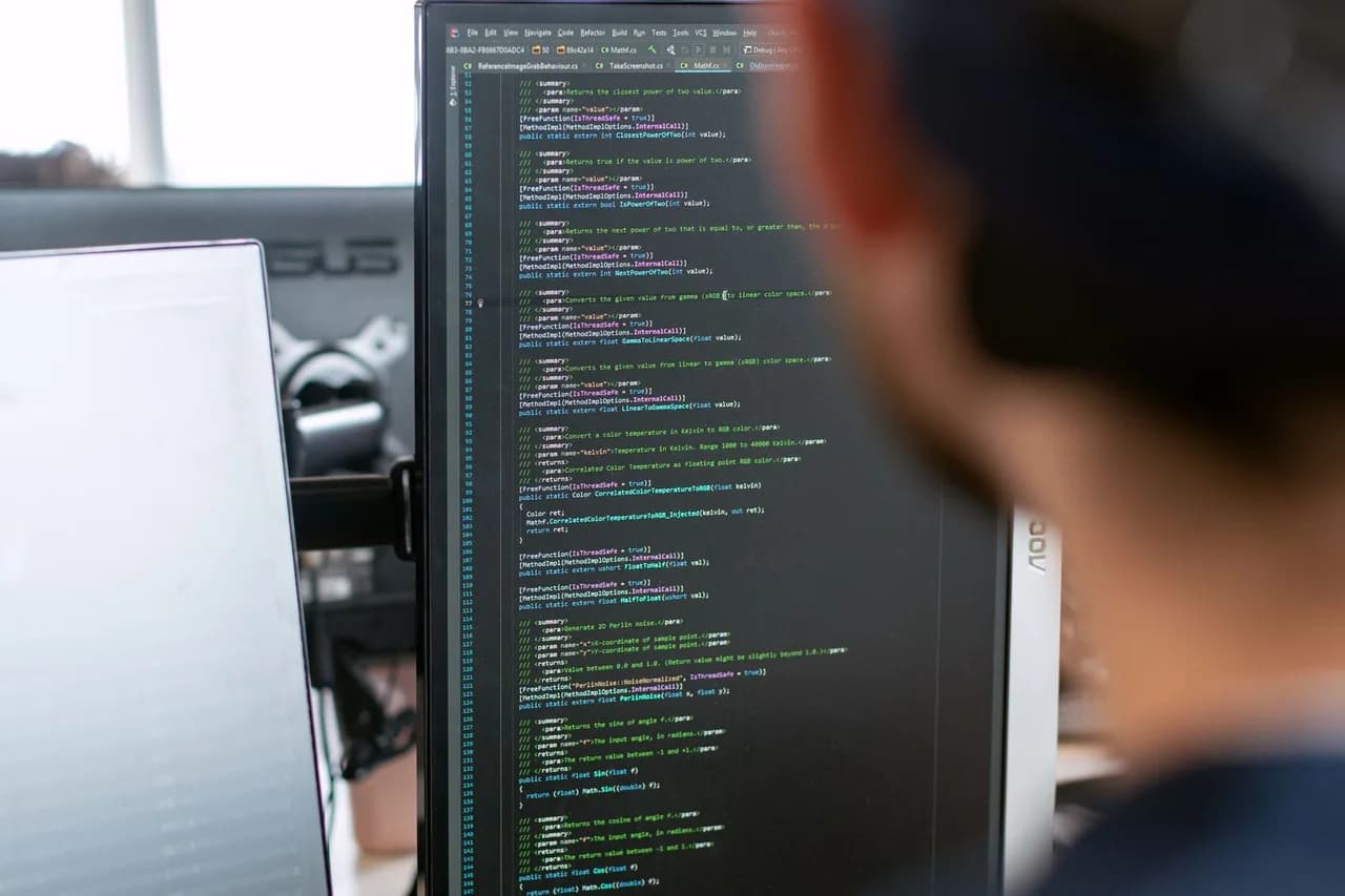 Developer writing application code on a multi-monitor workstation — custom Odoo Community module development in Python and QWeb